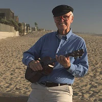 man playing ukelele on beach