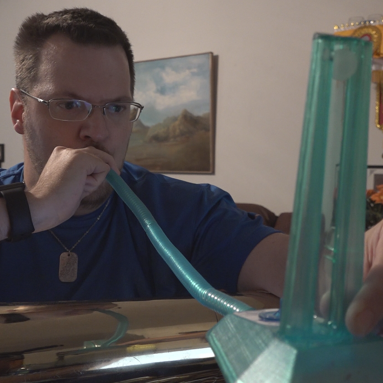   Rob Johnson uses a wind instrument tool to strengthen his breathing