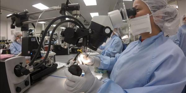 woman looking into microscope, testing device